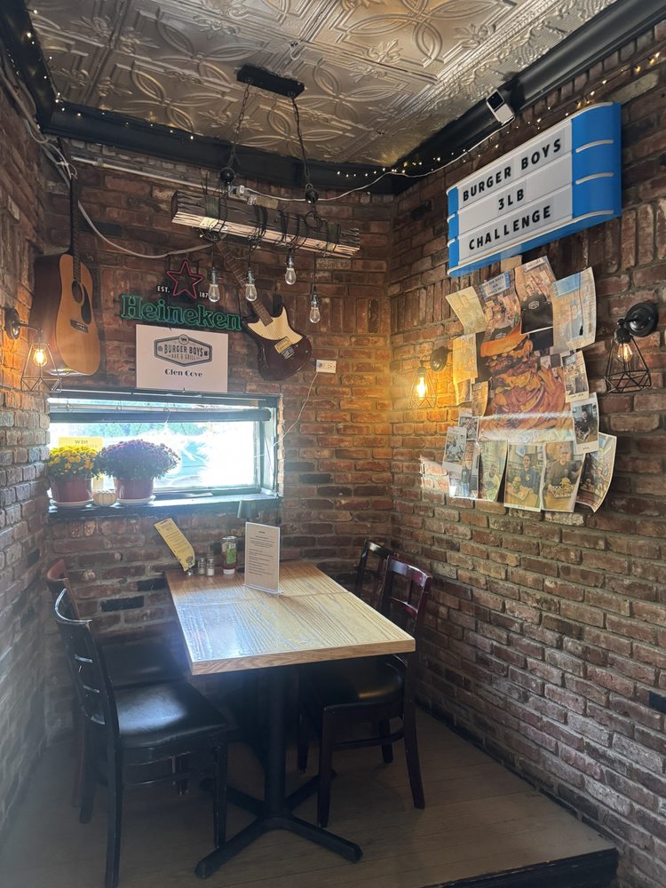 Brick-walled dining nook with guitars, string lights and the Burger Boys 3lb Challenge sign