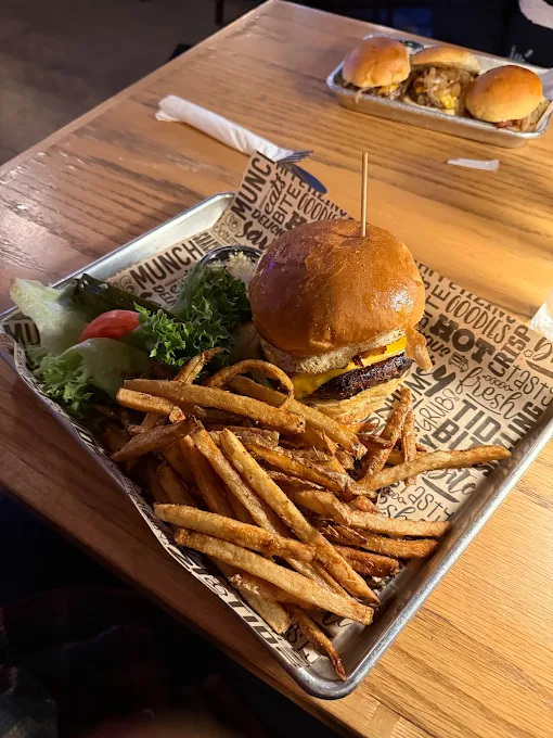 Cheeseburger with hand-cut fries and salad on a metal tray, sliders in the background